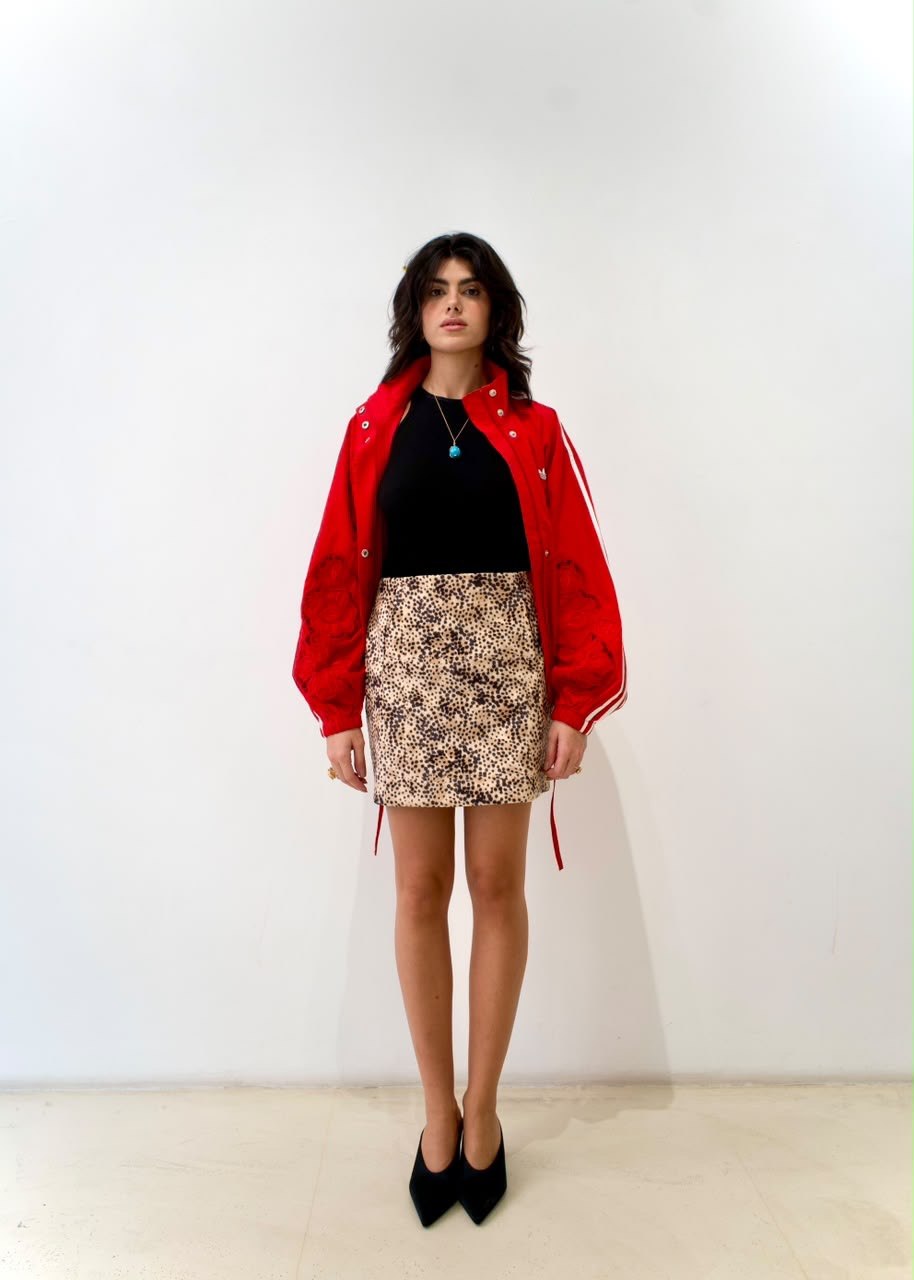 Full-length front styling view of the cheetah-print mini skirt with a black top and red jacket
