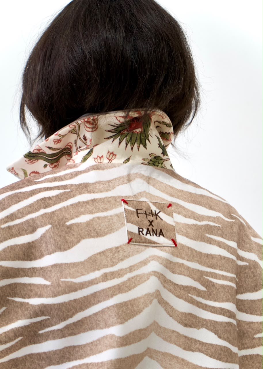 Back detail of the taupe-and-white zebra bomber jacket, showing the F++K x RANA patch and contrasting floral collar lining