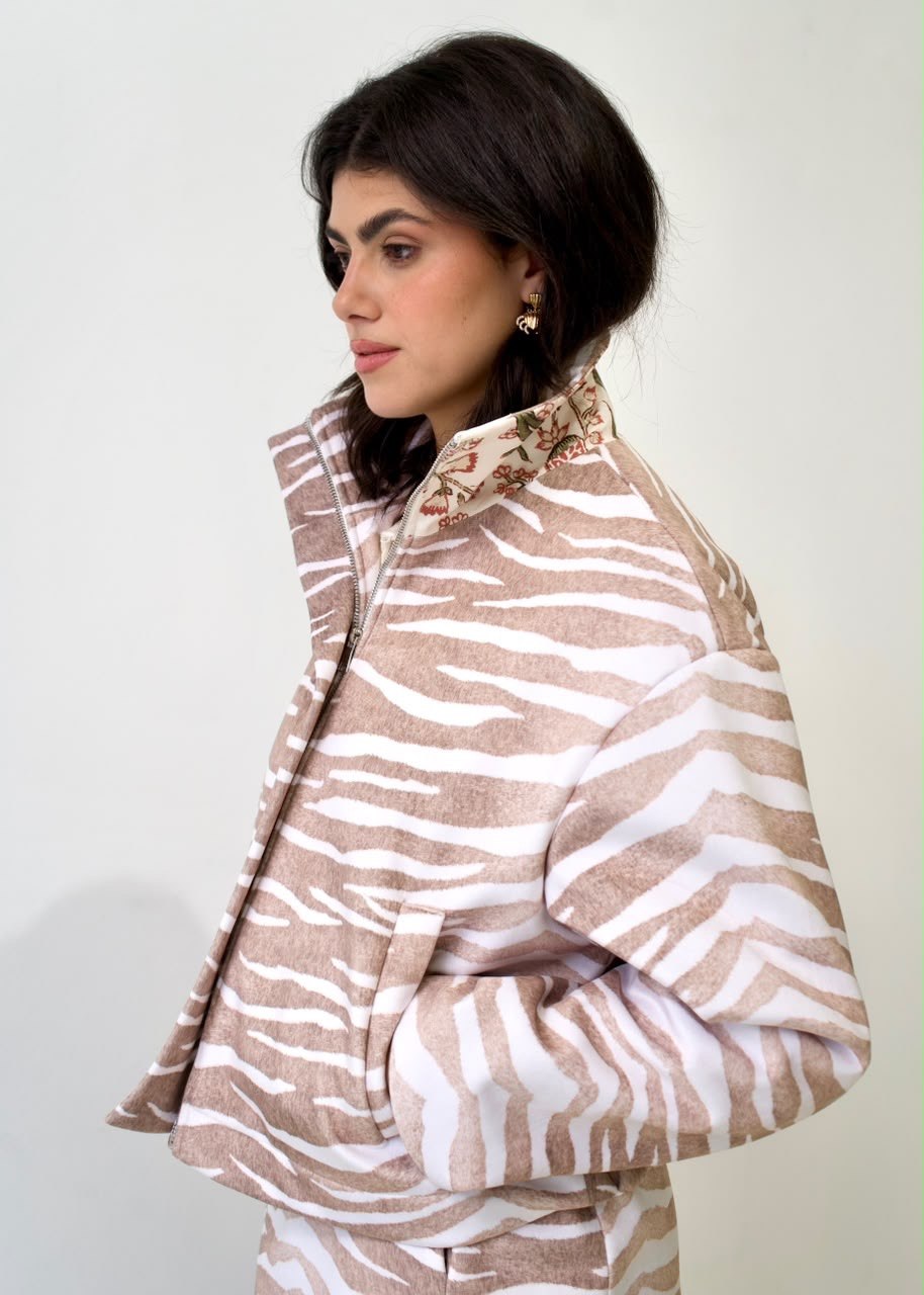Side detail of the taupe-and-white zebra bomber jacket, showing the raised floral-lined collar, zip fastening and front welt pocket